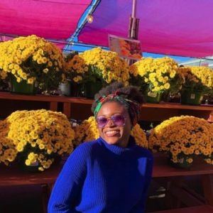 Mariam Sanusi standing in front of buckets of yellow flowers