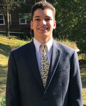 Lucas Ludgate standing outside with trees, grass, and a brick building in the background