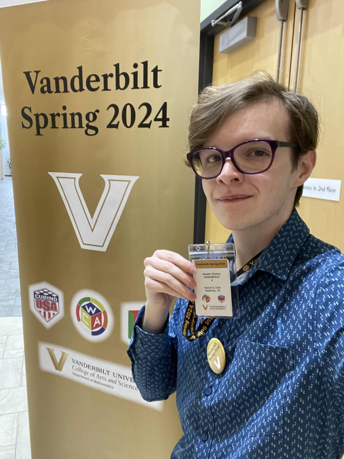Photo of Aussie holding up name badge in front of VU banner
