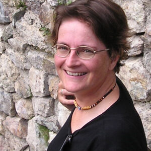 Woman smiling standing in front of stone wall