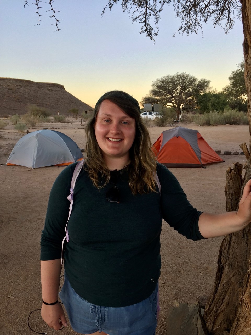 Kat in the field standing in front of some tents and smiling
