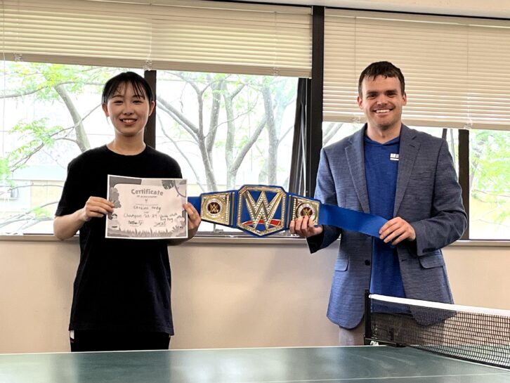 Two people standing holding championship belt