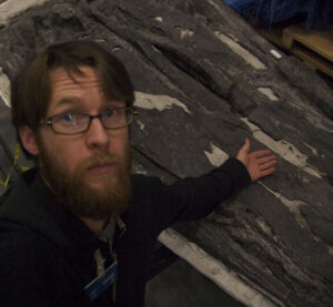 Neil in glasses pointing to some rocks