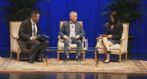 Prof. Carpenter (left), George Takei (center), and Alyson Win (A'20) on stage against blue curtains.
