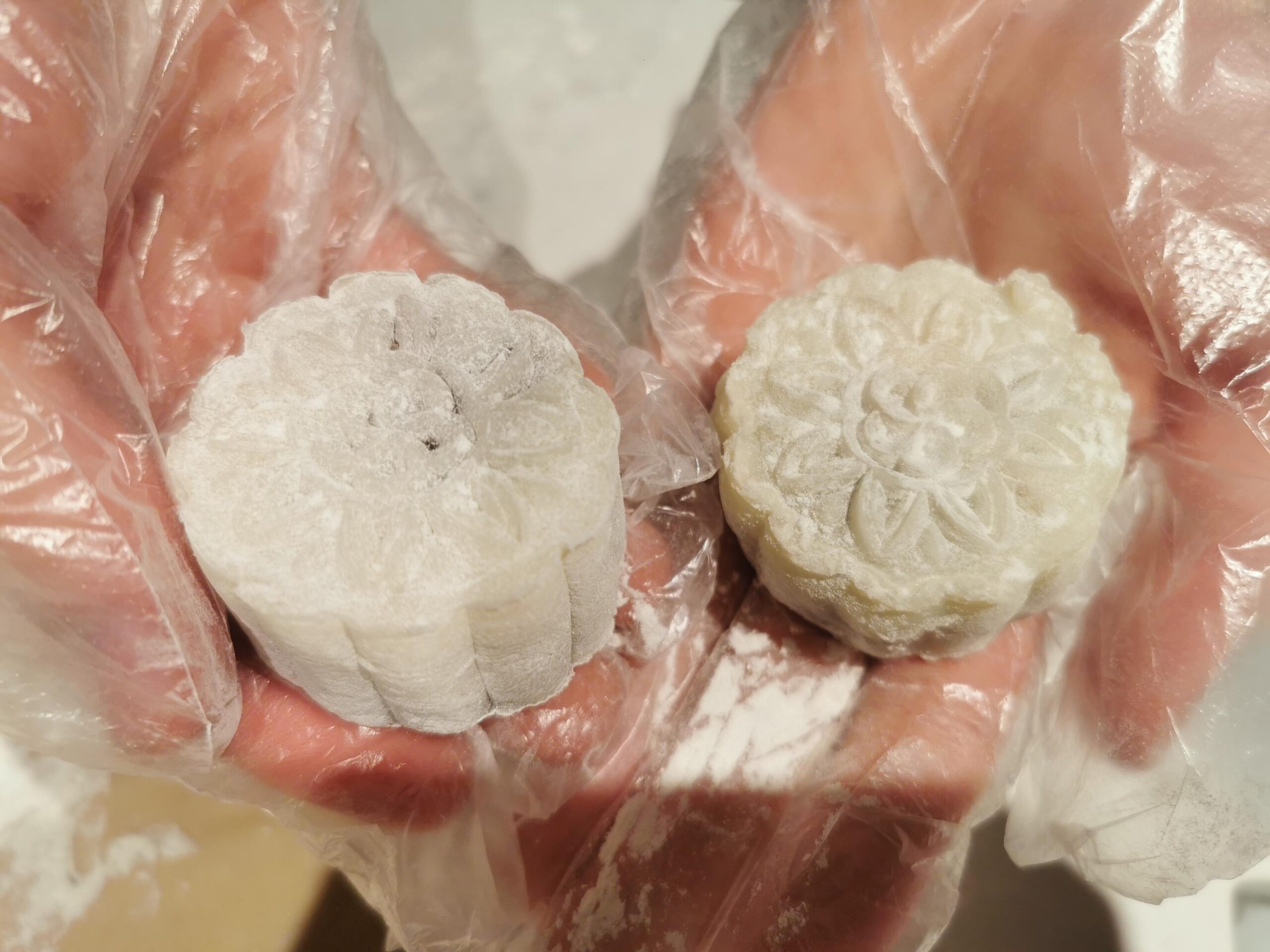 student holding 2 mooncakes with decorative flower pattern stamped on top