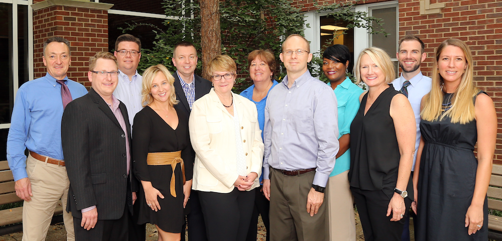 All the faculty of Communication Studies smiling to the camera in front of the Curb Center