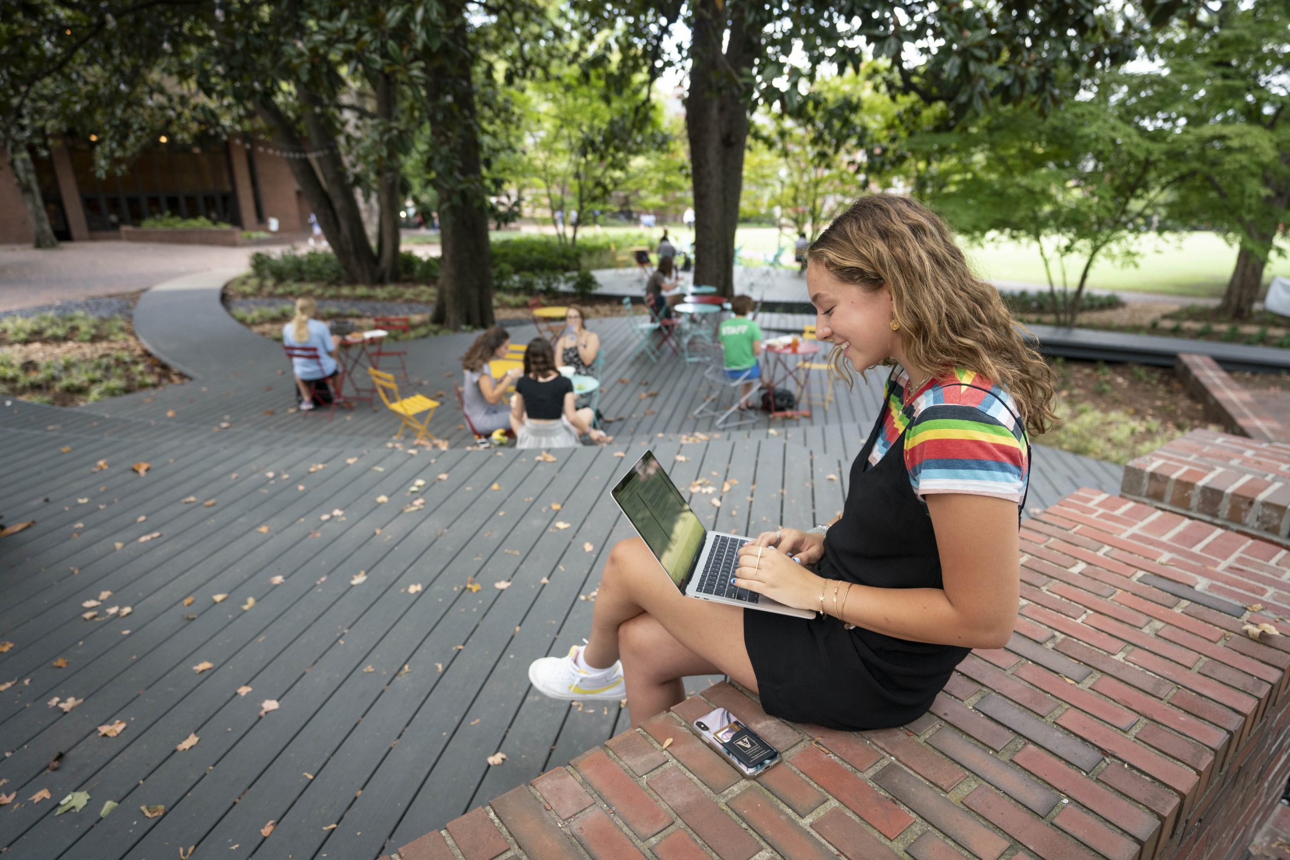 student working on a laptop outside on campus