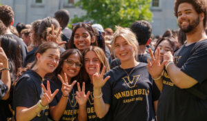 Four first-year students wearing matching black Vanderbilt shirts show the VU hand sign at Move-in