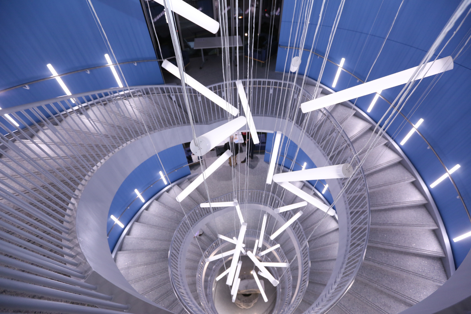 A spiral staircase with hanging lights in the middle.