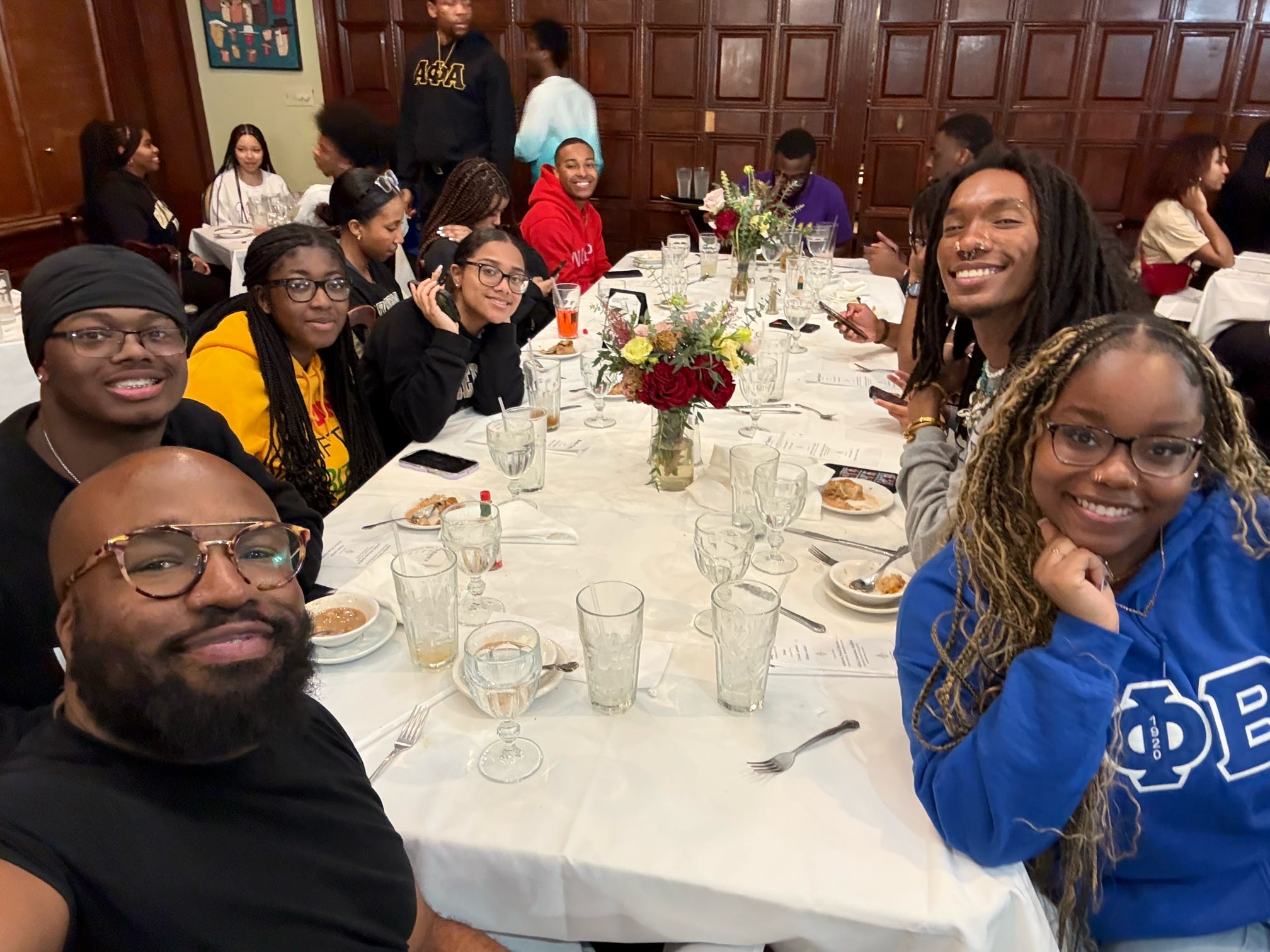 Group of students and staff members smiling at a dinner table.