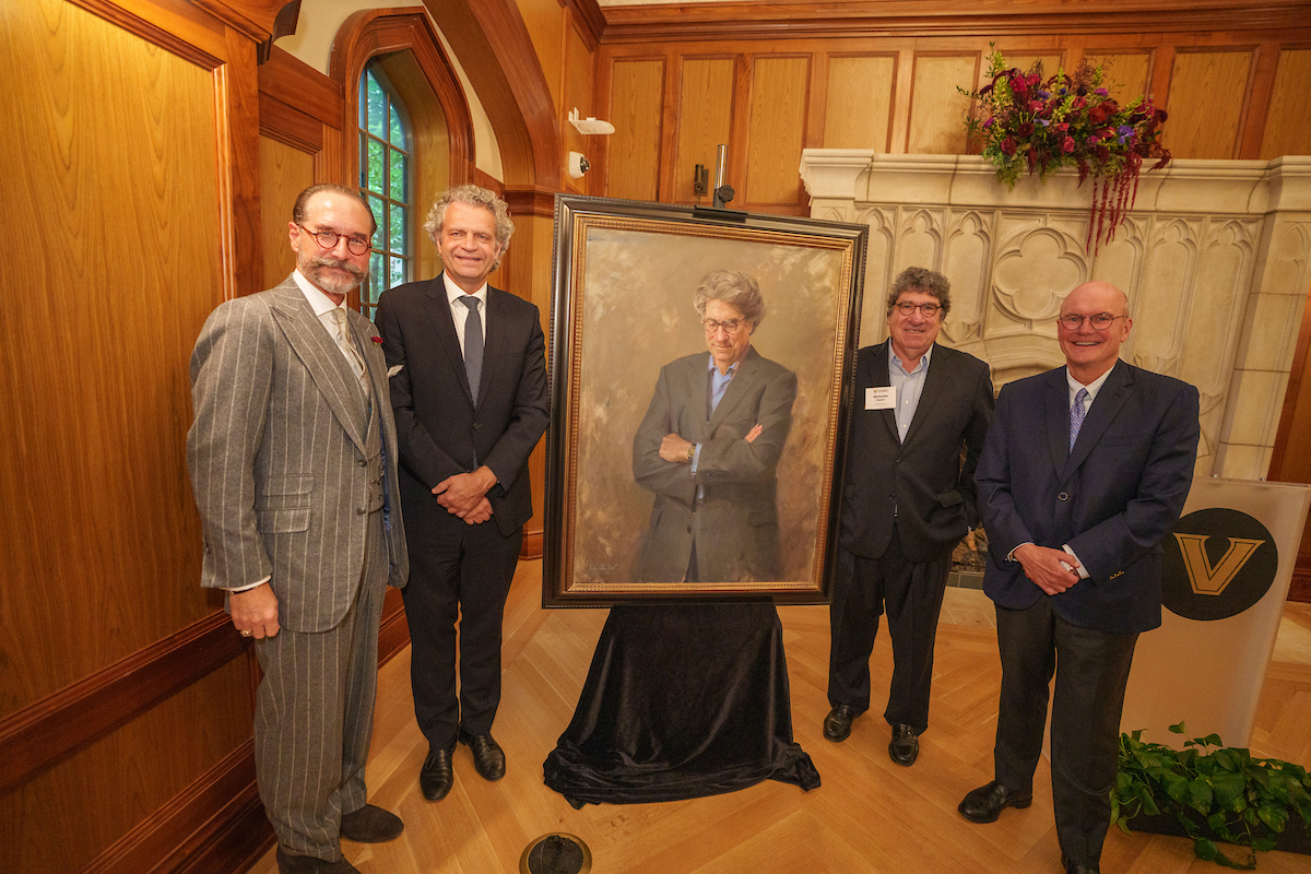 Four men standing, flanking a potrait
