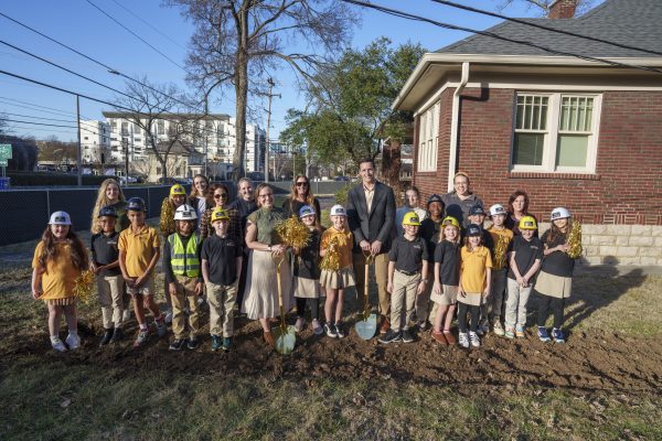Large group of students and teachers wear hardhats as they prepare to break ground on the future Roberts Academy.