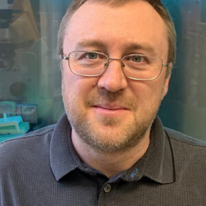 Sergei in glasses smiling with a blue shirt