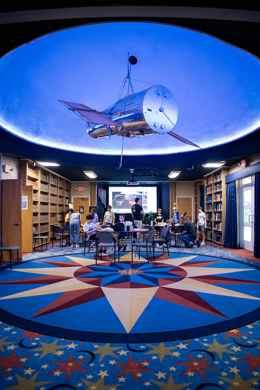 Students gather in the colorful observatory library beneath a model space telescope at Vanderbilt Dyer Observatory.
