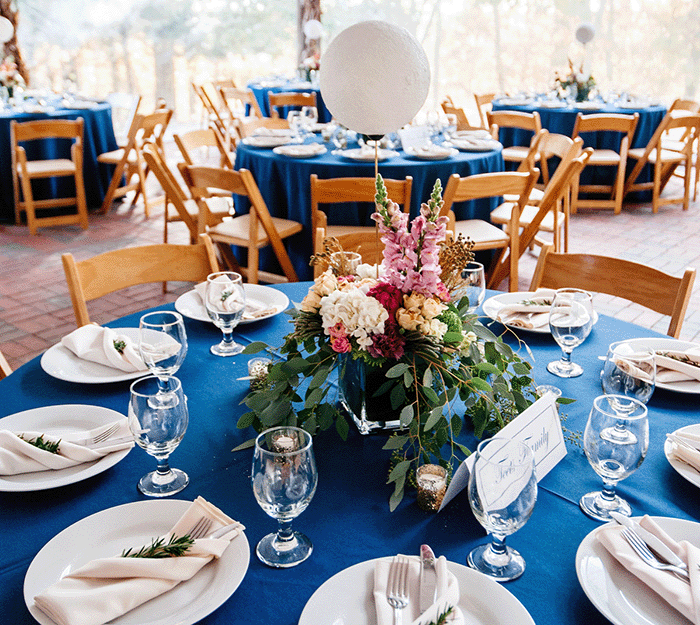 view of a formal table setting with floral centerpiece, other similar tables shown in background on the Dyer Observatory covered patio