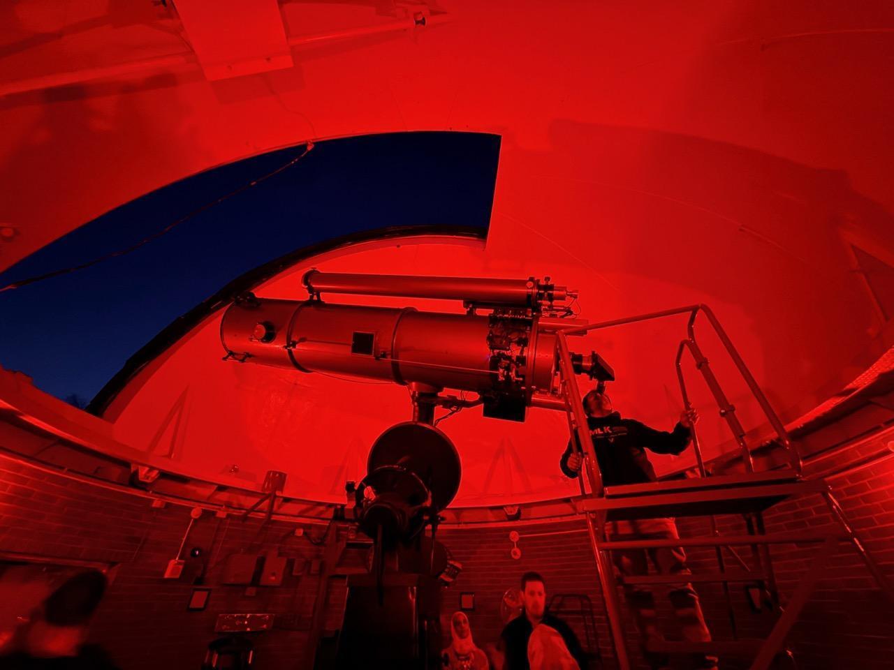 A student gazes through a telescope out at the night sky
