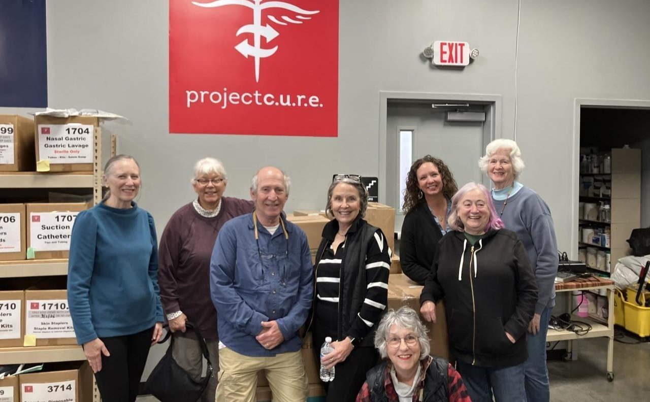 Group of volunteers smiling at Project C.U.R.E., surrounded by medical supply boxes