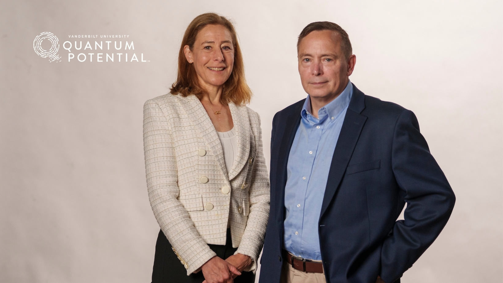 Image Description: Provost Raver and Professor Craig Lindsey standing and smiling in front of the Quantum Potential logo.. 