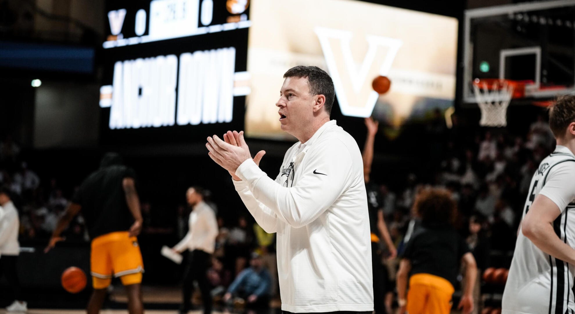 Men's basketball coach Mark Cyington claps on court during game warm-ups versus Tennessee.