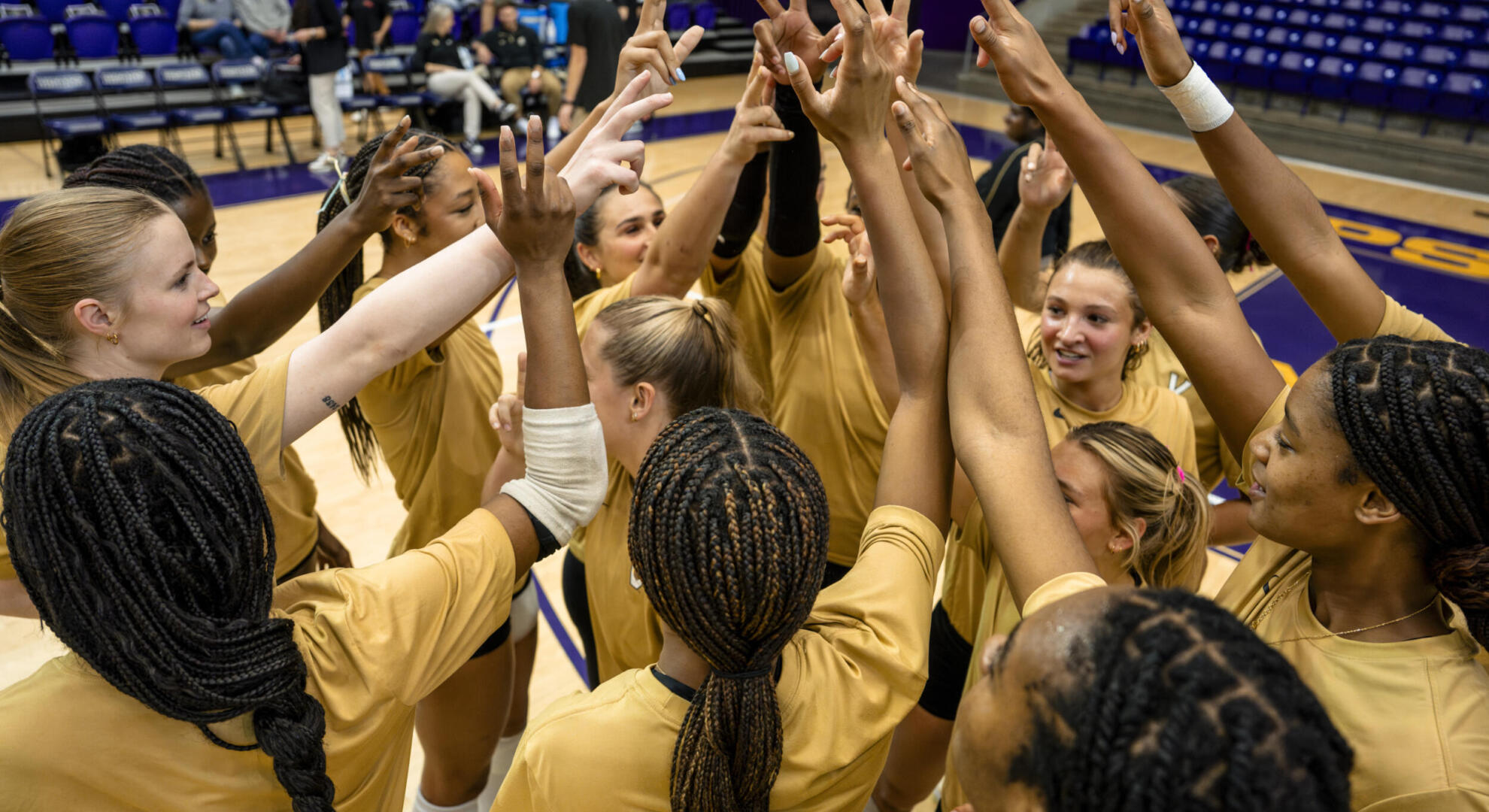 Volleyball team members join their hands together for a cheer before a game. 