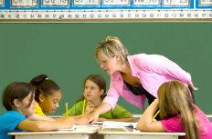 Teacher helping students at their desks.