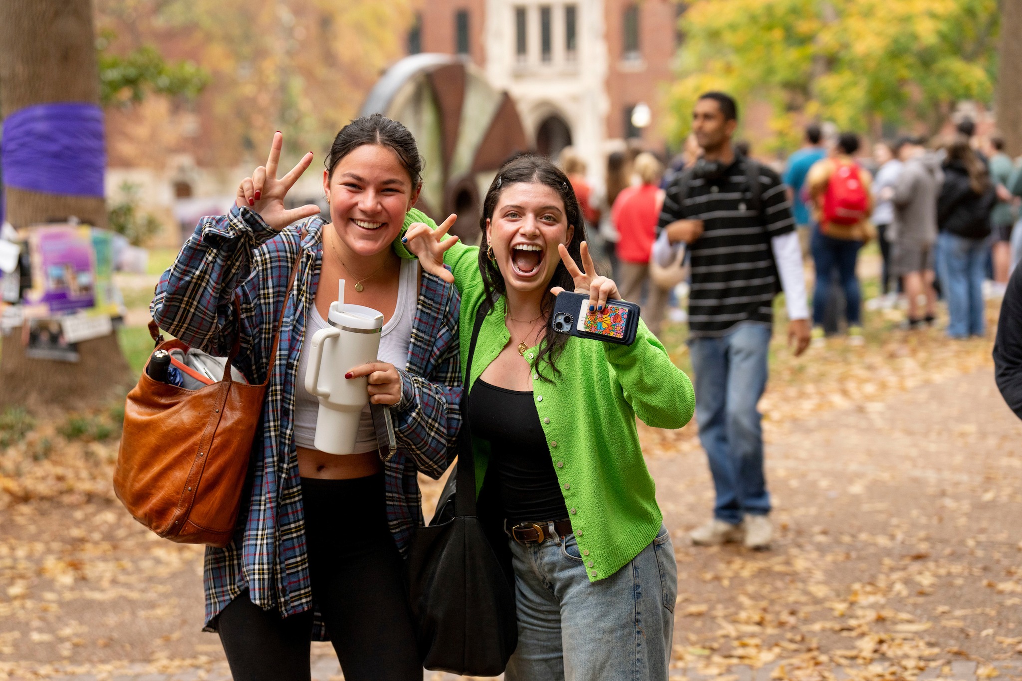 Two students give the Vanderbilt "V" hand sign while smiling during a fall day on campus.