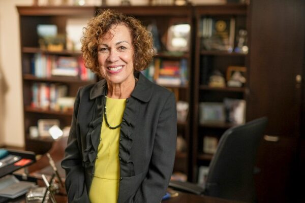 environmental photograph of Pamela Jeffries standing in front of bookcase