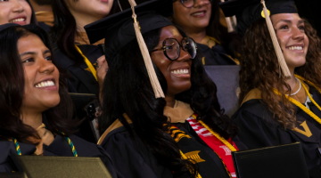 Pictured: A group of new Vanderbilt Business alum stand together for a photo in their cap and gown.