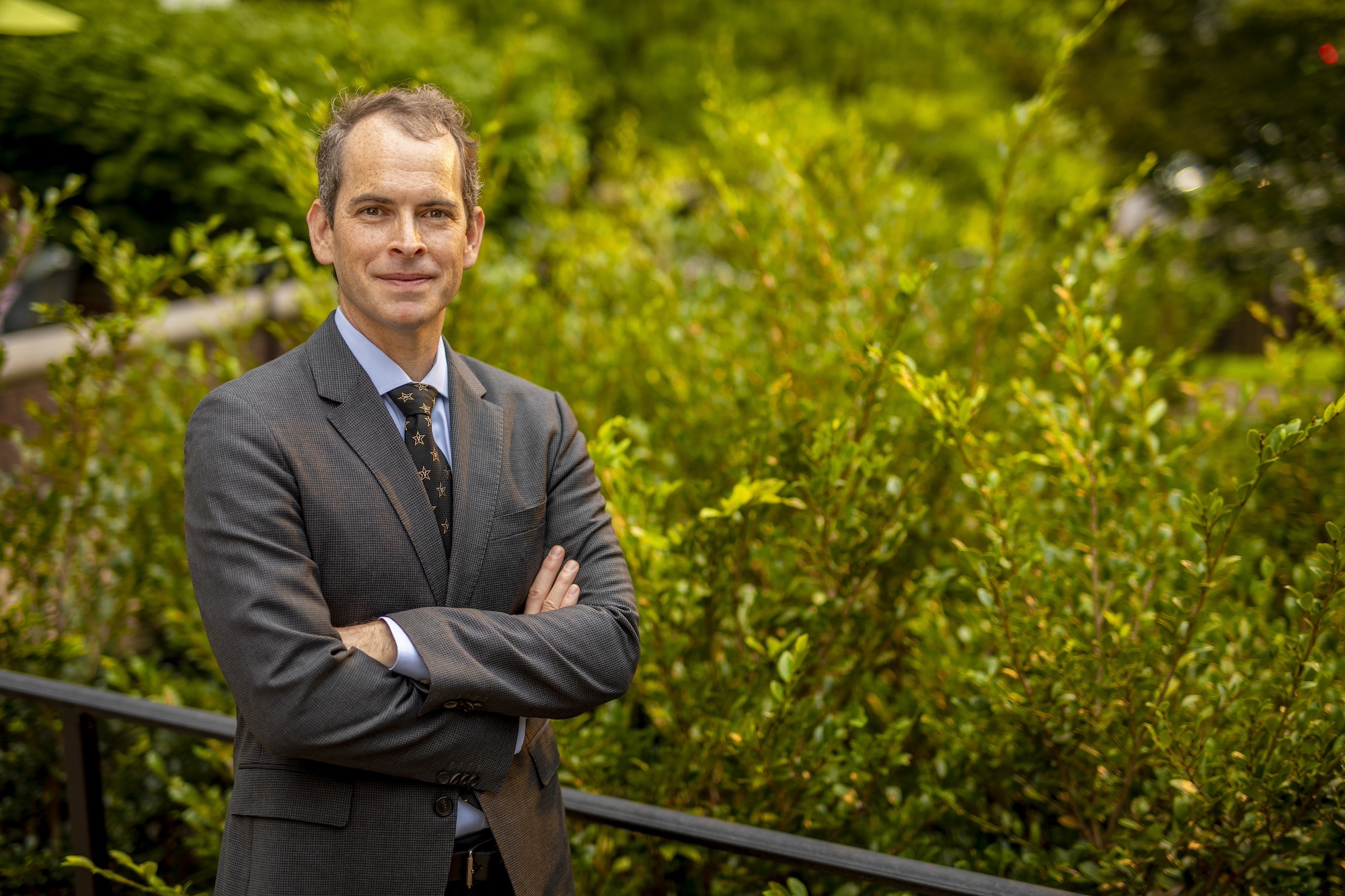 Josh Clinton stands in front of greenery on campus