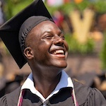 A student smiles in their commencement regalia