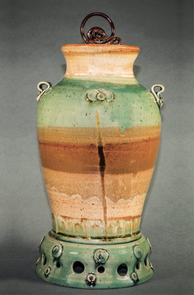 This tall, earth-tone glazed vase is one of Susan DeMay’s classroom demonstration pieces, 17x8x8 inches, completed in stages throughout a semester for an assignment involving numerous objectives for honing pottery wheelwork techniques. Photo by Bill Luton