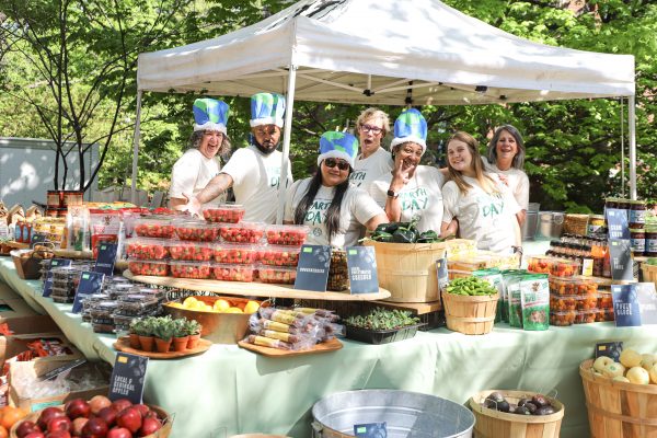 A group standing in front of strawberries, pepper, okra and tomatoes. 