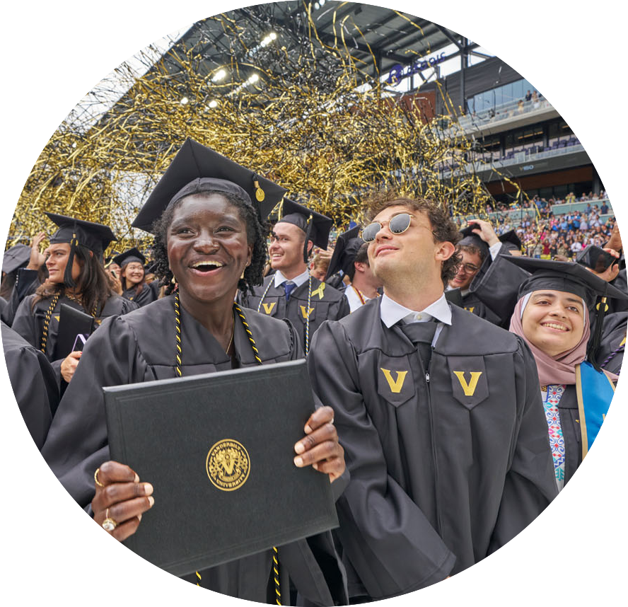 Group of smiling graduates in black robes and mortarboards, celebrating at commencement ceremony.