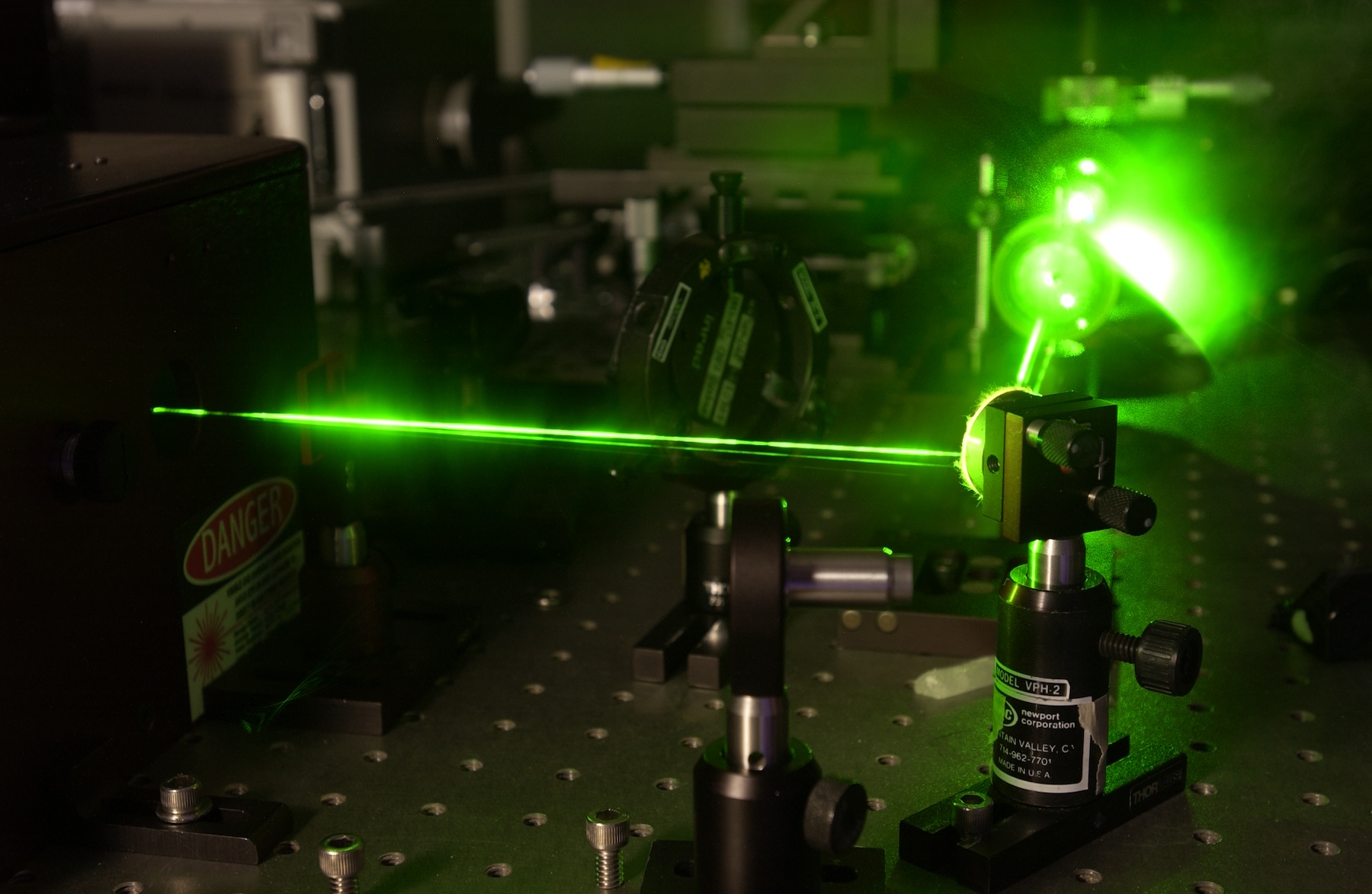 A green laser shooting across a darkened lab
