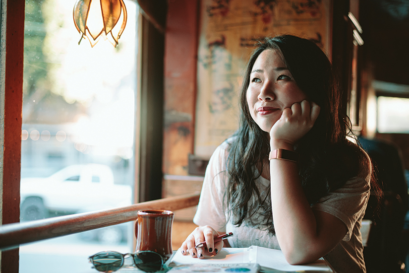 Jenny Qi sitting at a table looking off into the distance