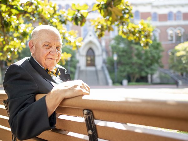 K.C. Potter, Vanderbilt dean emeritus of residential and judicial affairs, sitting on a bench with Kirkland Hall in the background