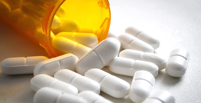 Close-up of knocked-over prescription bottle with white tablets spilling out
