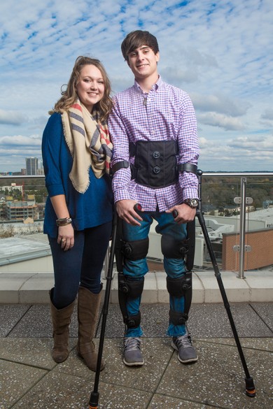 Indegouserweb man wearing exoskeleton and using crutches stands next to able-bodied woman