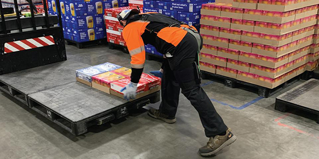 Worker lifts objects wearing HeroWear exosuit.
