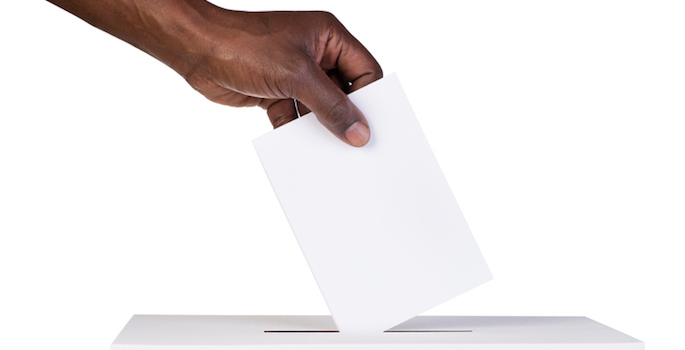 Ballot box with person casting vote on blank voting slip
