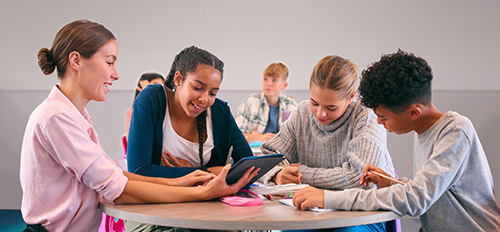 teacher and three students working at a small table
