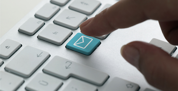 finger pressing a button marked with an envelope on a keyboard, signifying email