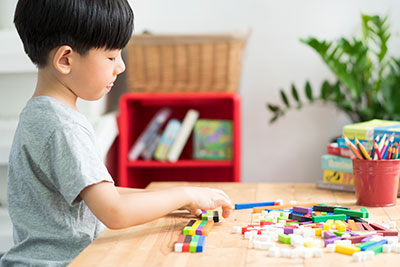 Boy playing with colored cubes at table