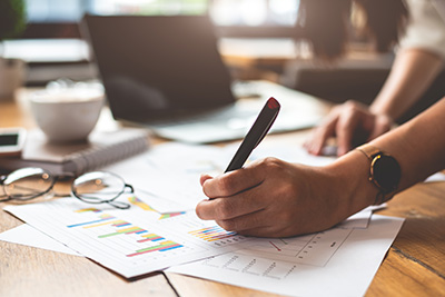 Person taking notes on printed graphs and spreadsheets