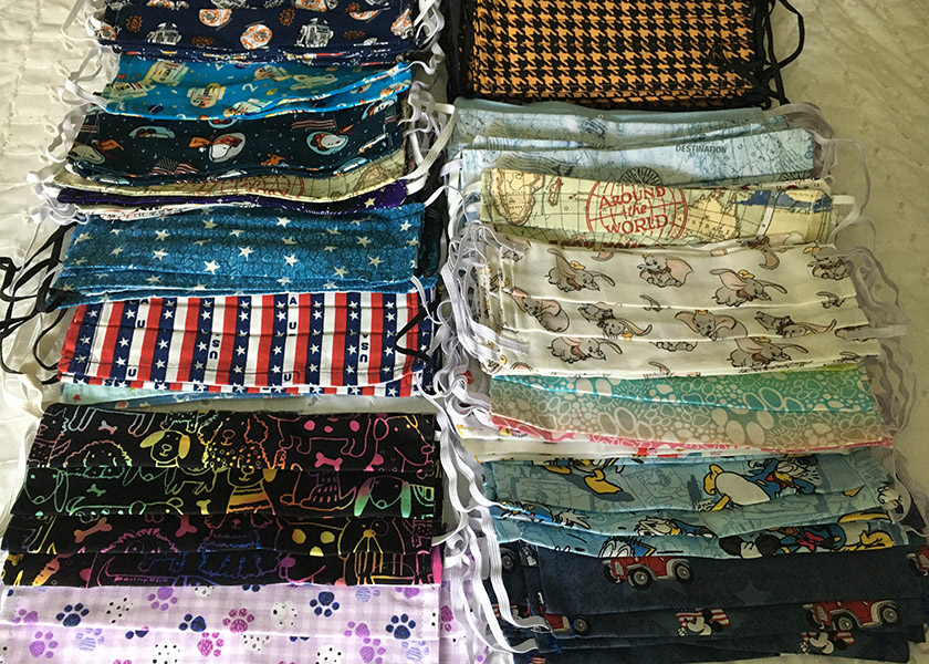 Dozens of handmade cloth masks are aligned in 2 rows