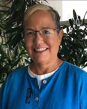 Professor Susan Dorsey stands in front of greenery