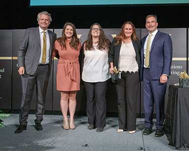Two men in suits, Chanceller Diermeier and Eric Kopstain , flank three women award winners