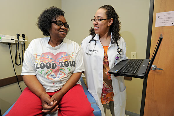 Vanderbilt family nurse practitioner student talks to a patient sitting on an exam table in a clinic.