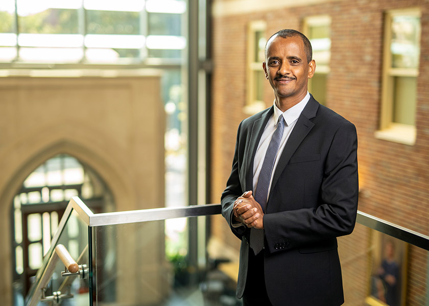 Mulubrhan Mogos in a suit stands on the staircase in VUSN's atrium