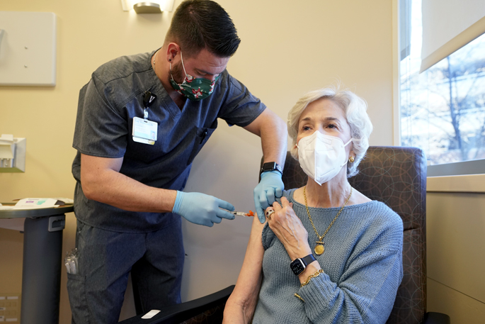 Cody Stubblefield, RN, gives the first of two injections of an antibody combination to Caroline Davis to protect her from COVID-19.